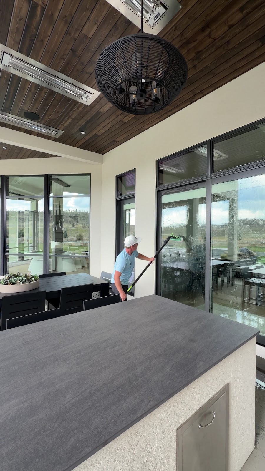 Scrub Squad crew member washing patio windows on a modern outdoor living space