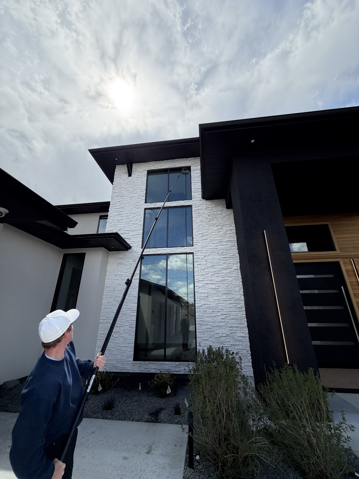MT Scrub Squad technician using an extension pole to clean tall entryway windows